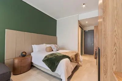 a bedroom with a bed and a green wall at Capital City Luxury Apartment 830 Menlyn Maine in Pretoria
