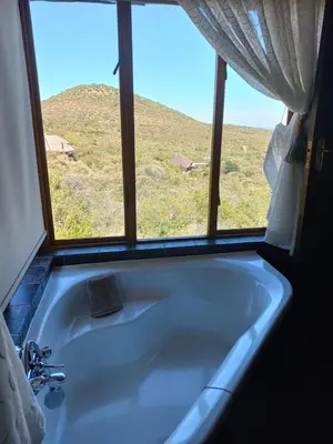 a bath tub with a window with a view of a hill at Mafuta Lodge - Mabalingwe Nature Reserve in Warmbaths