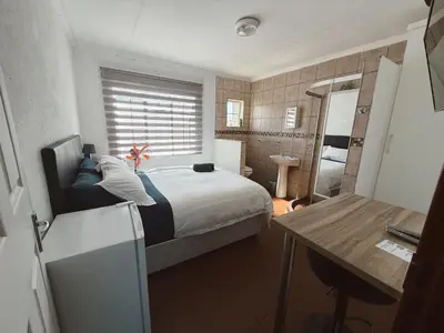 a small bedroom with a bed and a bathroom at Rooikrans Guest House Mpumalanga in Boschfontein