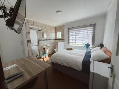 a small bedroom with a bed and a desk at Rooikrans Guest House Mpumalanga in Boschfontein