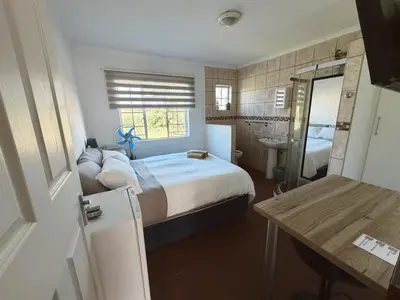 a bedroom with a large bed and a bathroom at Rooikrans Guest House Mpumalanga in Boschfontein