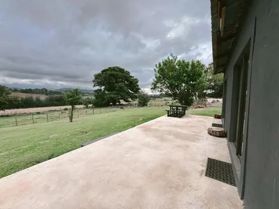 a walkway next to a building with a grass field at Rooikrans Guest House Mpumalanga in Boschfontein