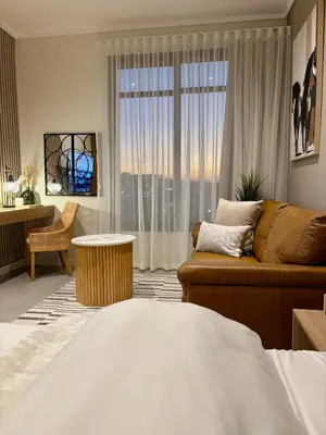 a living room with a couch and a large window at Modern Studio in Menlyn Maine in Pretoria