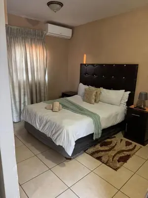 a bedroom with a large bed with a black headboard at Kioma guest house mahwelereng in Mokopane
