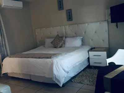 a bedroom with a large bed with a padded headboard at Kioma guest house mahwelereng in Mokopane