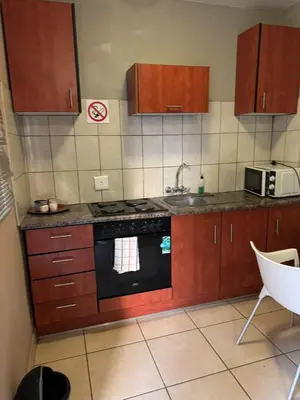 a kitchen with wooden cabinets and a stove top oven at Kioma guest house mahwelereng in Mokopane