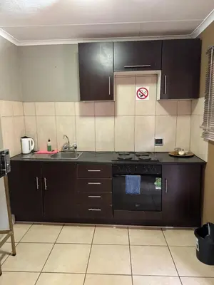 a kitchen with black cabinets and a stove top oven at Kioma guest house mahwelereng in Mokopane