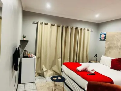a bedroom with a bed with a red blanket at De'Lush Oasis in Pretoria