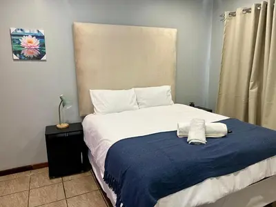 a bed with a blue blanket and white pillows at De'Lush Oasis in Pretoria