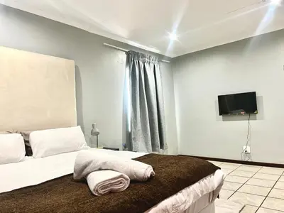 a bedroom with a bed and a flat screen tv at De'Lush Oasis in Pretoria