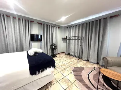 a bedroom with a bed and a couch and a table at De'Lush Oasis in Pretoria