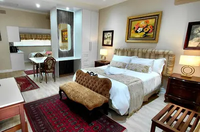 a bedroom with a bed and a chair and a table at Royal Ridge Guesthouse in Pretoria