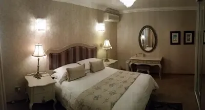 a bedroom with a large bed and a mirror at Royal Ridge Guesthouse in Pretoria