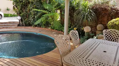 a small pool on a wooden deck with a table and chairs at Royal Ridge Guesthouse in Pretoria