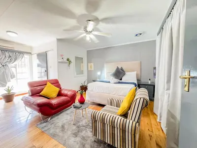 a bedroom with a bed and a couch and a chair at Berry Bliss Haven in Pretoria