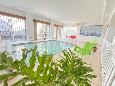 a large indoor pool with green chairs and plants at Berry Bliss Haven in Pretoria