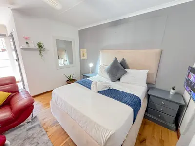a bedroom with a large bed and a red couch at Berry Bliss Haven in Pretoria