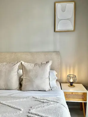 a bedroom with a bed with white pillows and a table at Kurhula Suite Apartment in midrand in Midrand