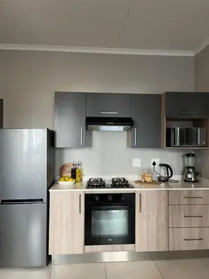a kitchen with a stove and a refrigerator at Kurhula Suite Apartment in midrand in Midrand