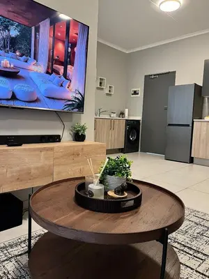 a living room with a table and a tv at Kurhula Suite Apartment in midrand in Midrand