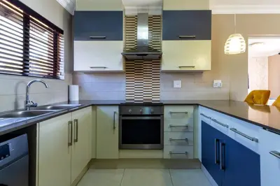 a kitchen with white and blue cabinets and a sink at Alimamaspaces The Mansons Riverbend Midrand in Midrand