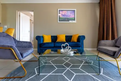 a living room with a blue couch and two chairs at Alimamaspaces The Mansons Riverbend Midrand in Midrand