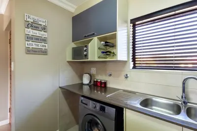 a kitchen with a sink and a washing machine at Alimamaspaces The Mansons Riverbend Midrand in Midrand