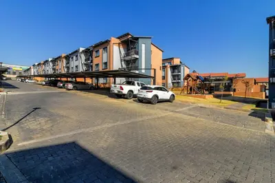an empty street with cars parked in front of buildings at AlimamaSpaces Bonitos Waterfall Ridge in Midrand