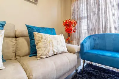 a living room with a couch and a blue chair at AlimamaSpaces Bonitos Waterfall Ridge in Midrand