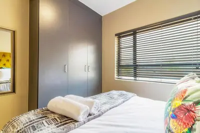 a bedroom with a bed and a window with blinds at AlimamaSpaces Bonitos Waterfall Ridge in Midrand