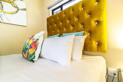 a bedroom with a large white bed with a yellow headboard at AlimamaSpaces Bonitos Waterfall Ridge in Midrand