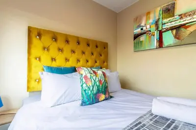 a bedroom with a white bed with a yellow headboard at AlimamaSpaces Bonitos Waterfall Ridge in Midrand