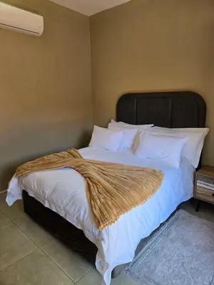 a large bed with white sheets and a brown blanket at Cozy Lifestyle Guesthouse in Naboomspruit
