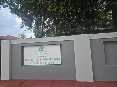 a white retaining wall with a sign on it at Cozy Lifestyle Guesthouse in Naboomspruit