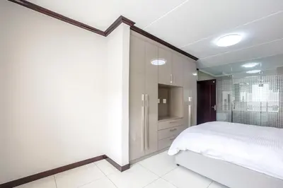 a bedroom with a white bed and a shower at AlimamaSpaces The Manson's Walford in Midrand
