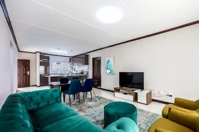 a living room with a green couch and a dining room at AlimamaSpaces The Manson's Walford in Midrand