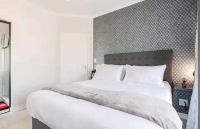 a bedroom with a large white bed with a patterned wall at AlimamaSpaces The Chelsea's Kikuyu in Midrand
