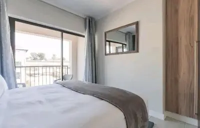 a bedroom with a bed with a mirror and a window at AlimamaSpaces The Chelsea's Kikuyu in Midrand