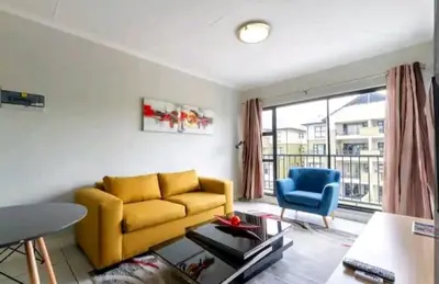a living room with a yellow couch and a blue chair at AlimamaSpaces The Chelsea's Kikuyu in Midrand