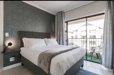 a bedroom with a large bed and a balcony at AlimamaSpaces The Chelsea's Kikuyu in Midrand