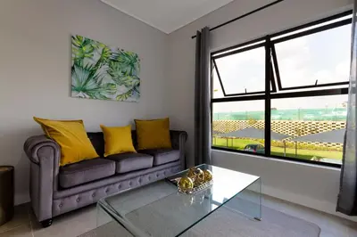 a living room with a couch and a glass table at AlimamaSpaces The Chelsea's Munyaka in Midrand