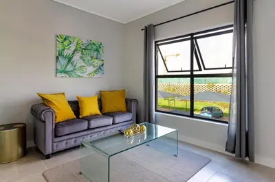 a living room with a couch and a glass table at AlimamaSpaces The Chelsea's Munyaka in Midrand