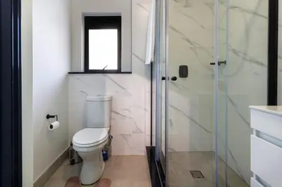 a bathroom with a toilet and a glass shower at AlimamaSpaces The Chelsea's Munyaka in Midrand