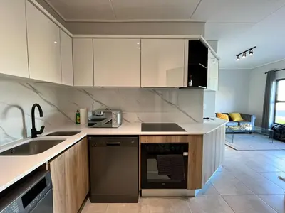 a kitchen with white cabinets and a sink at AlimamaSpaces The Chelsea's Munyaka in Midrand