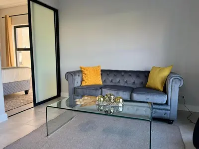 a living room with a blue couch and a glass table at AlimamaSpaces The Chelsea's Munyaka in Midrand