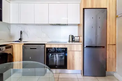 a kitchen with a stainless steel refrigerator and a glass table at AlimamaSpaces The Munyakas Manson 1543 in Midrand