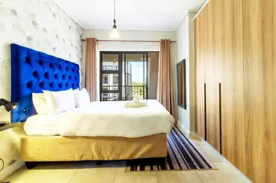 a bedroom with a large bed with a blue headboard at AlimamaSpaces The Munyakas Manson 1543 in Midrand