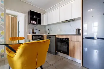 a kitchen with a table and a yellow chair at AlimamaSpaces The Munyakas Manson 1543 in Midrand