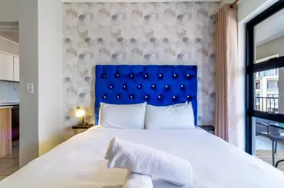 a bedroom with a large bed with a blue headboard at AlimamaSpaces The Munyakas Manson 1543 in Midrand