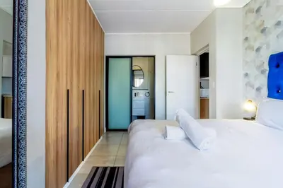 a bedroom with a large white bed and a mirror at AlimamaSpaces The Munyakas Manson 1543 in Midrand